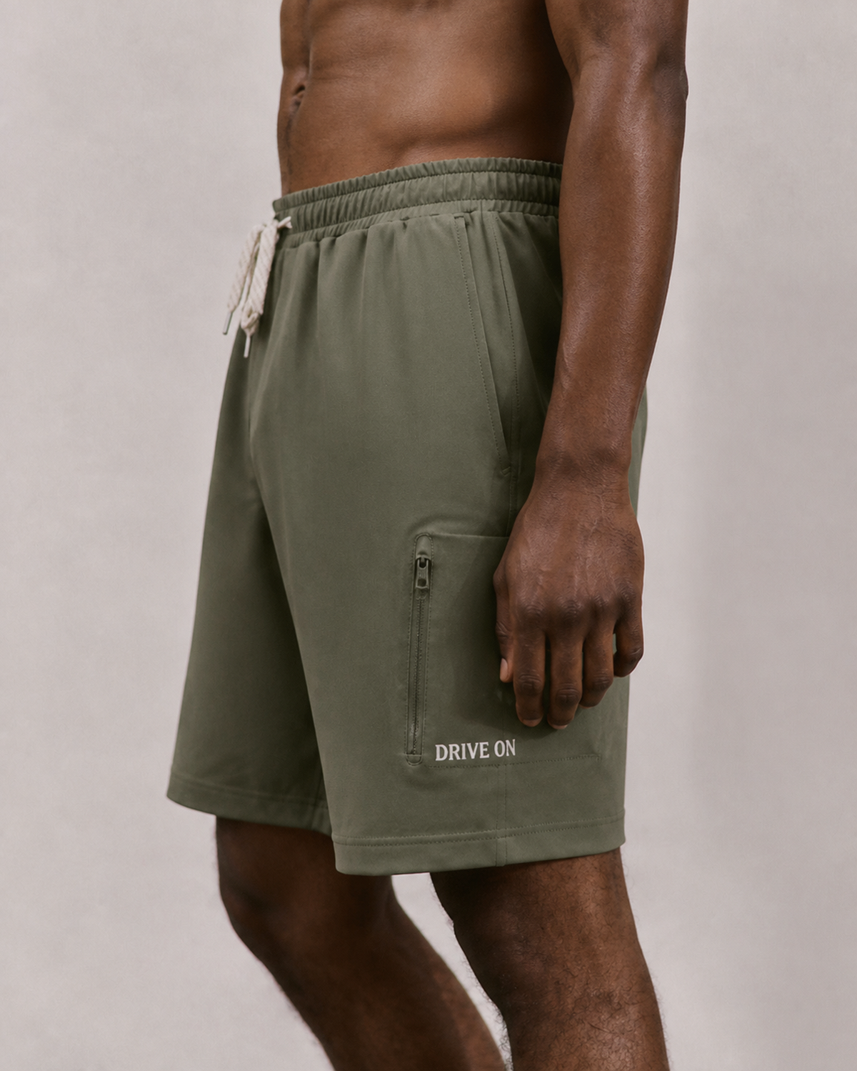 Close-up of olive green cargo shorts with a DRIVE ON wordmark above the side pocket