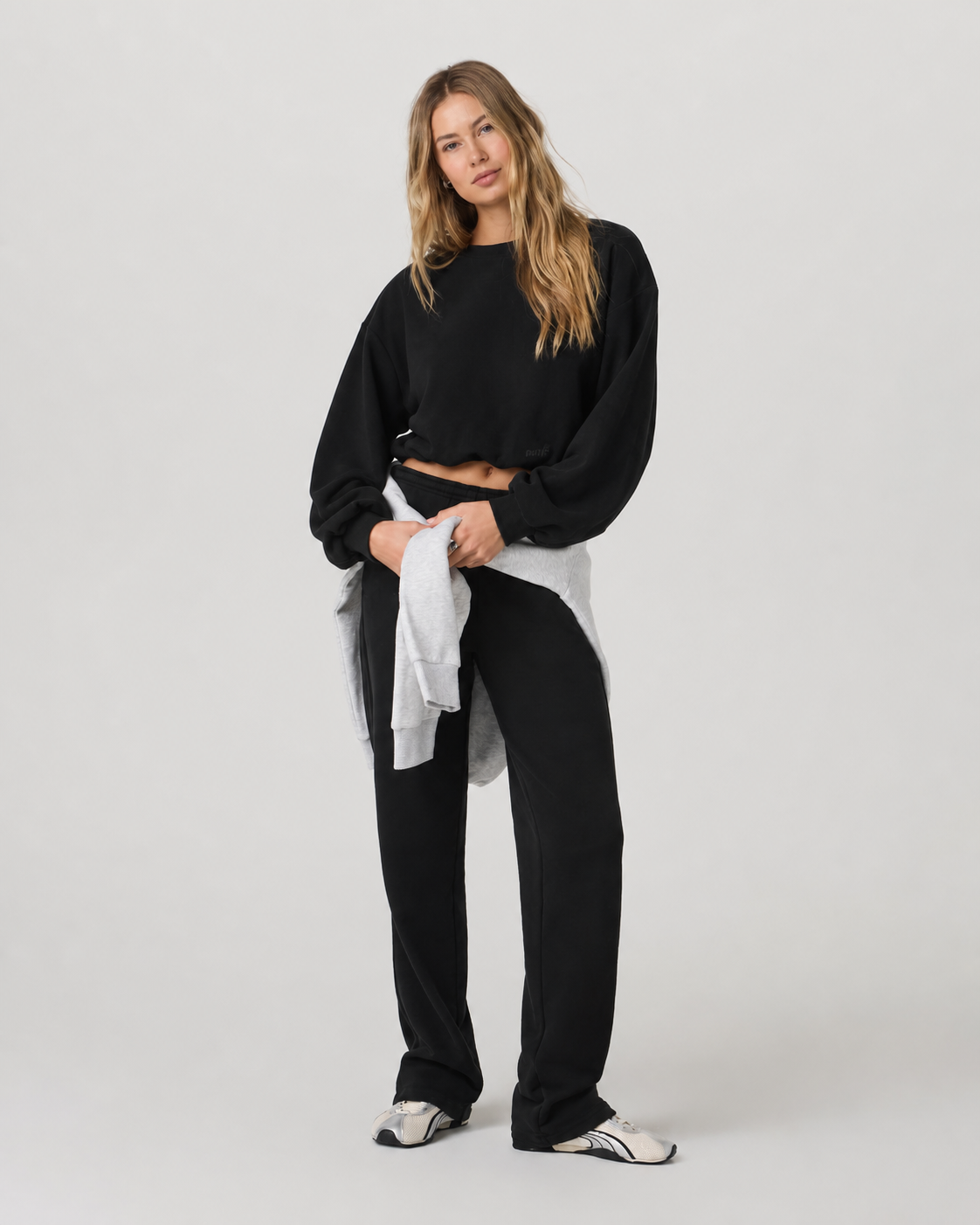 A cropped black sweatshirt worn with black wide-leg pants, a light grey layer tied at the waist